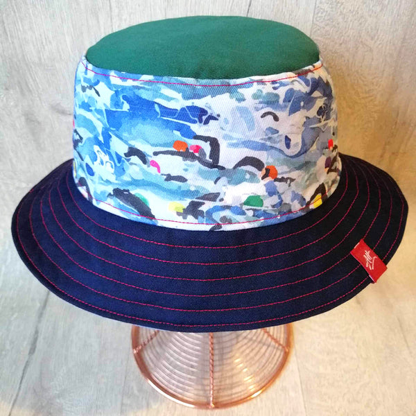 Reversible swimmer's festival bucket hat featuring open water swimmers