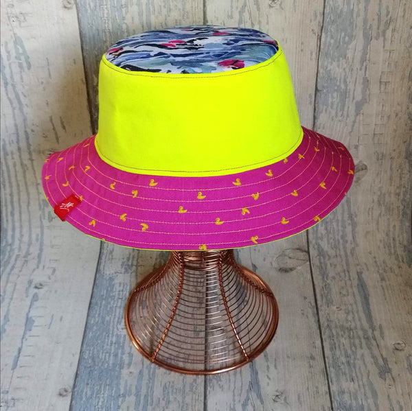 Reversible neon bucket hat with Andrea's iconic Mass Start swimmers design yellow and pink