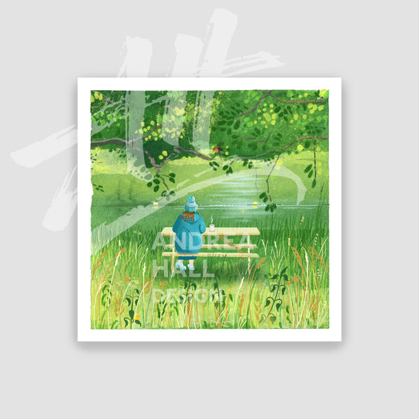 A small square art print featuring an illustration of a person sitting on a bench by a lake, surrounded by lush green trees and grass. The print is displayed against a light gray background.