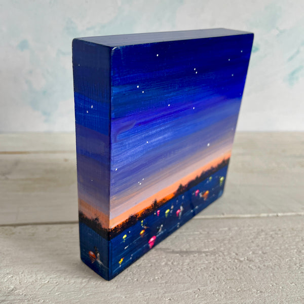Rectangular block with a gradient design from blue to orange, resembling a sunset over water with swimmers.