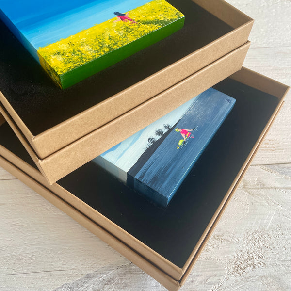 a stack of two tiny paintings in their display boxes
