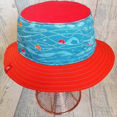 Reversible swimmer's festival bucket hat featuring outdoor swimmers
