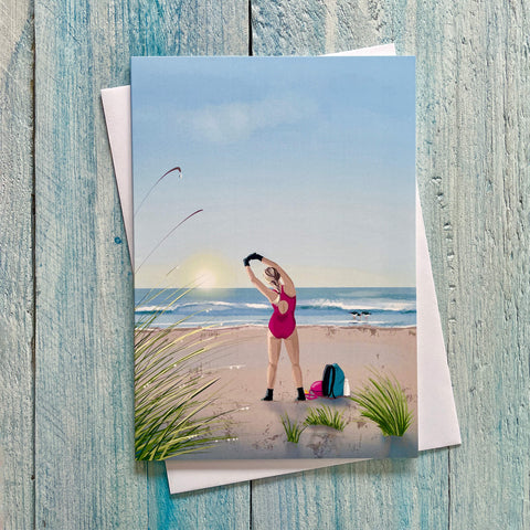 Greetings card illustration of a wild swimmer stretching on the beach at sunrise.