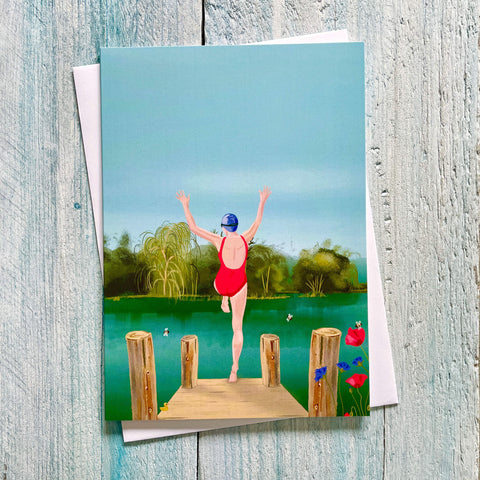 Greeting card with a person in a red swimsuit standing on a wooden jetty over water, with trees and flowers in the background.