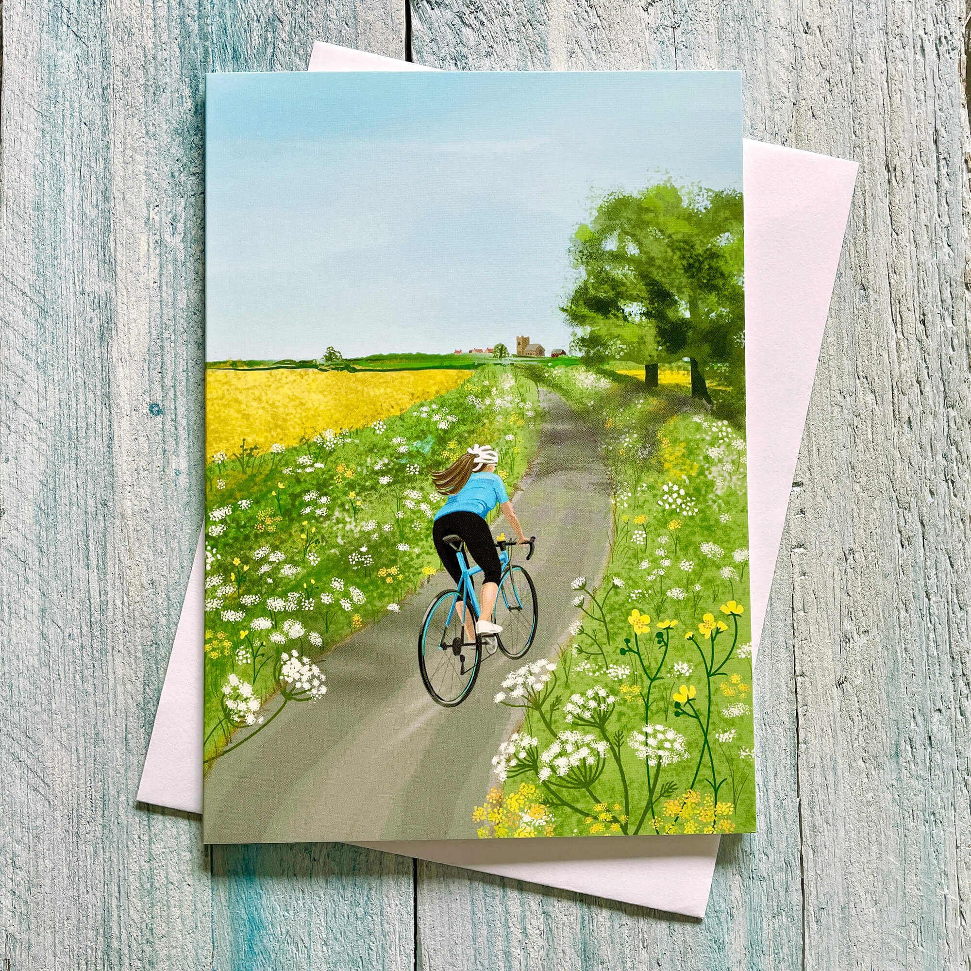 Greeting card with a cyclist on a path surrounded by flowers and trees