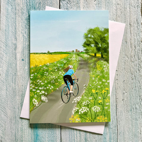Greeting card with a cyclist on a path surrounded by flowers and trees