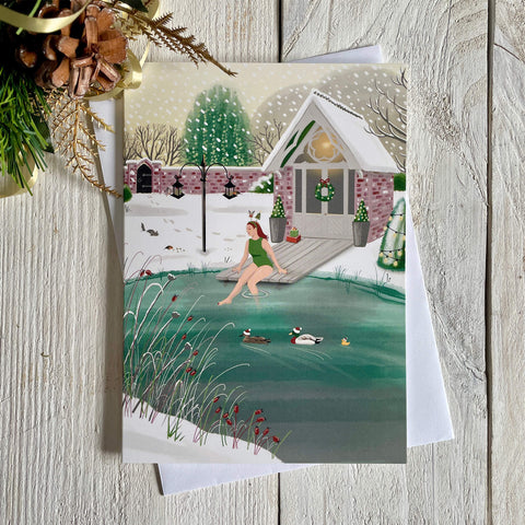 Christmas card with illustration of wild swimmer getting into her garden pond. Card with white envelope and a touch of Christmas decoration