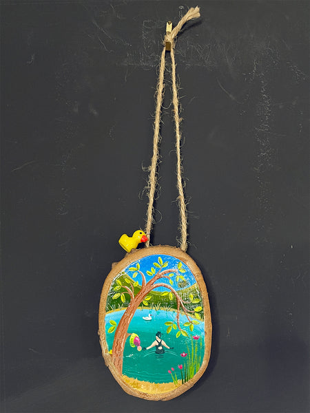 Original painted log slice decoration featuring a miniature wild swimming scene hanging against a blackboard background.