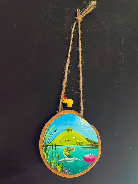 Original painted log slice decoration featuring a swimming scene hanging with a little Duck charm against a blackboard background.