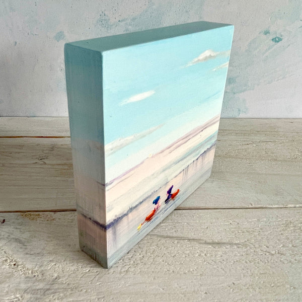 Rectangular block with a misty swimming scene painted on it, placed on a wooden surface.
