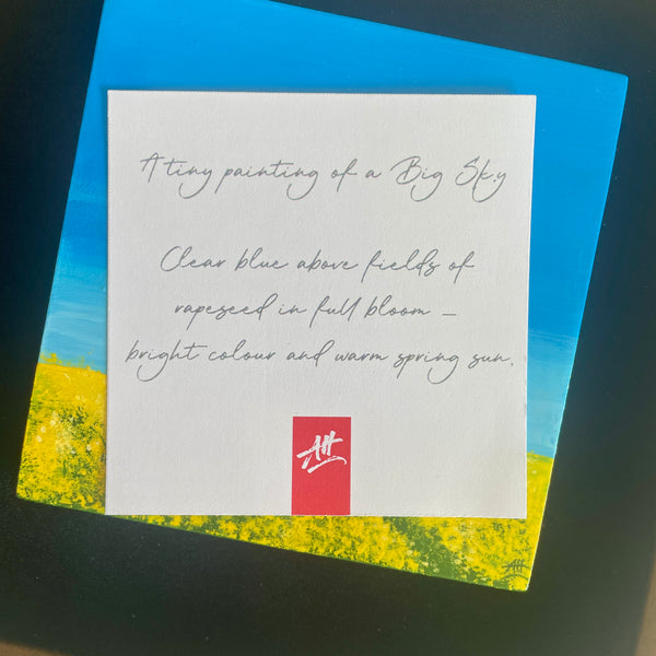 Close up of original miniature Big Sky painting of rapeseed fields beneath a blue sky. Presented in display box with descriptive label