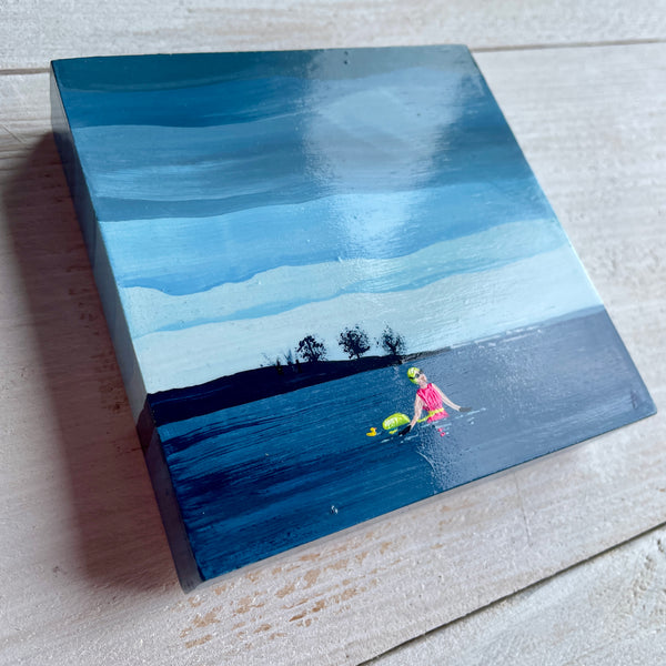 Small painting of a swimmer in a lake with stormy clouds and trees in the background, displayed at an angle to show off gloss varnish