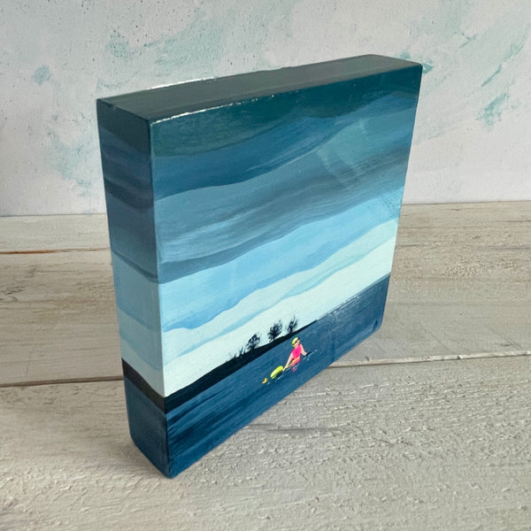 Original painting of a swimmer in a lake on a square wooden block, shown standing, at an angle