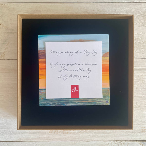 Boxed artwork with description card on a wooden surface