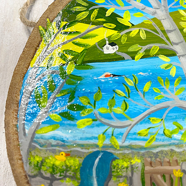 Close-up of spring swim illustration on round natural log slice with bark edge.