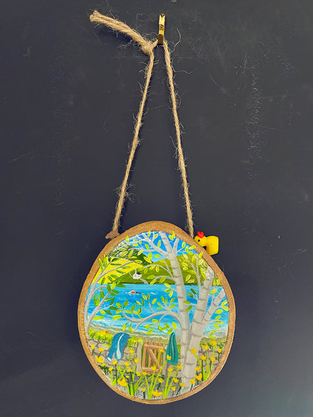 Original painted log slice decoration with a little Ducky charm hanging against a blackboard background.