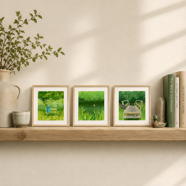 Three framed lsquare art prints depicting green wild swimming scenes, displayed on a wooden shelf next to books and decorative items against a warm beige wall.