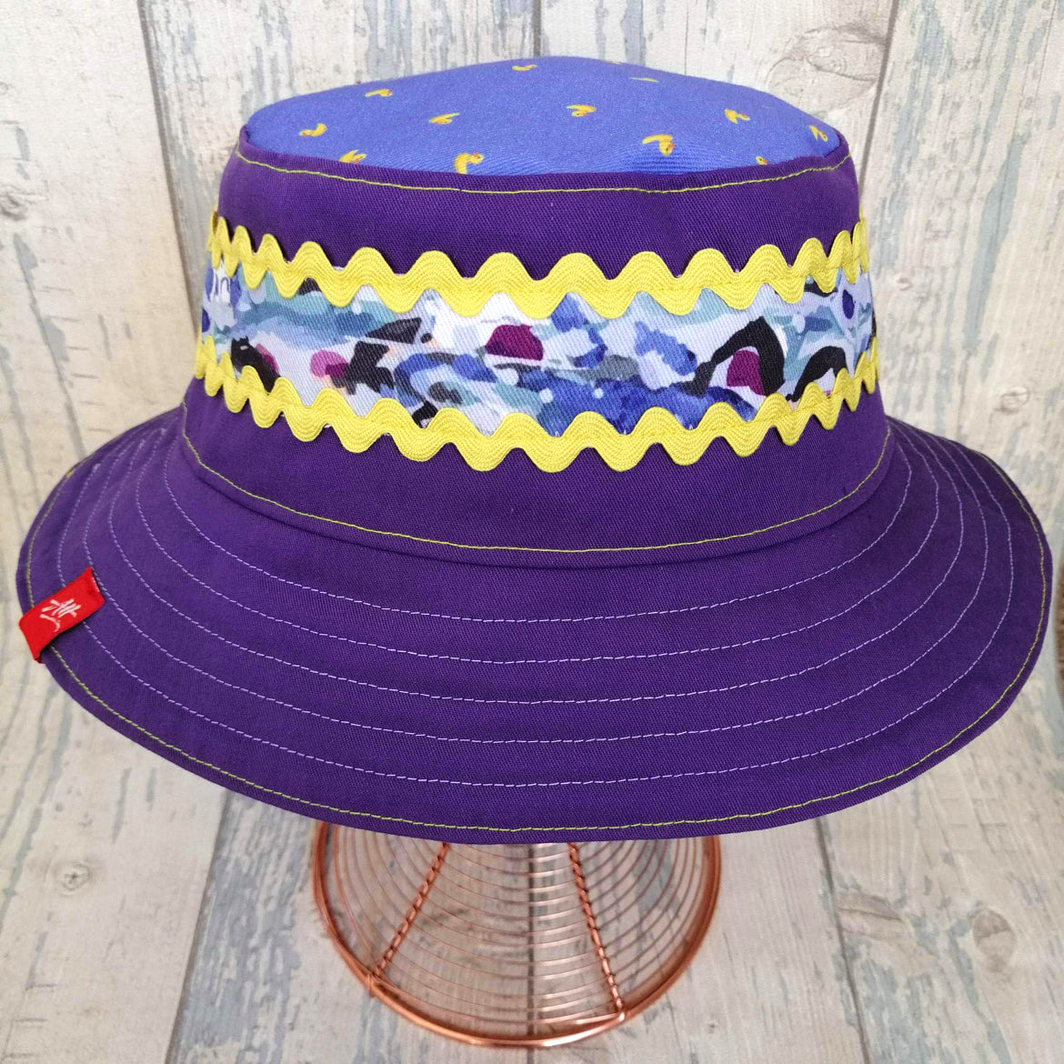 Reversible festival bucket hat in purple with yellow trim and swimmers