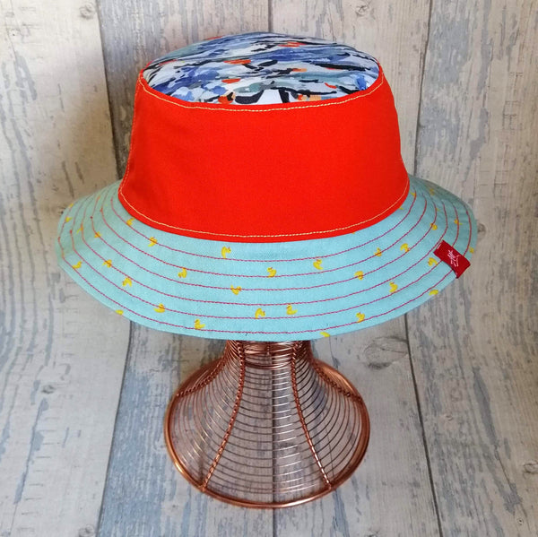 Orange reversible bucket hat with multi-colour Mass Start design