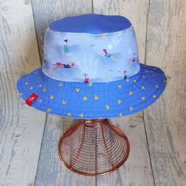 Reversible festival bucket hat in pastel cornflower blue with swimming ladies design